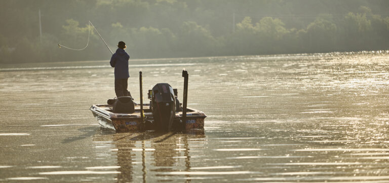 man in a boat on a lake at sunset